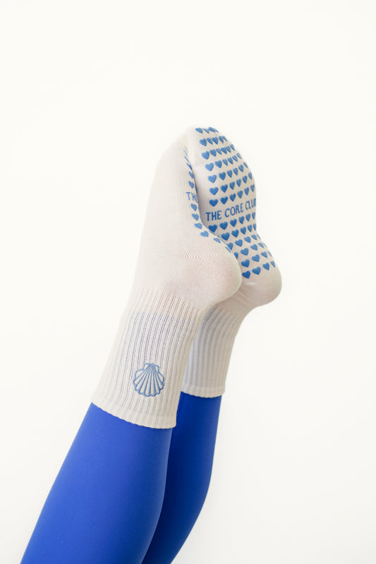 Seashell Grip Pilates Sock – white cotton non-slip socks with blue seashell detail & heart grippies. Unisex, one-size, perfect for Pilates, yoga & barre.