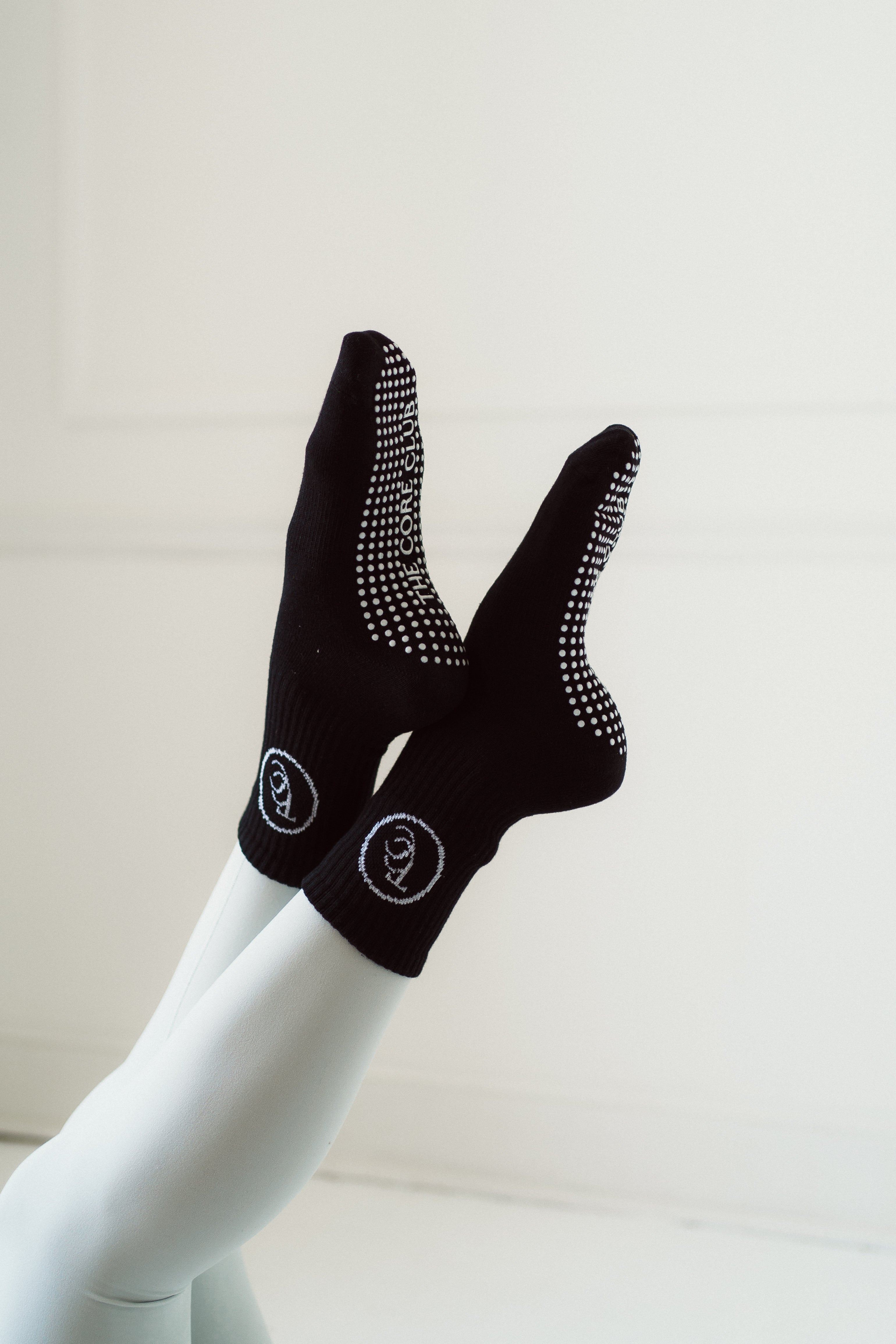 TCC Original Round Logo Grip Socks – jacquard logo Pilates socks in tan, black & white. Dot or heart grippies, one-size-fits-all, studio-ready style.
