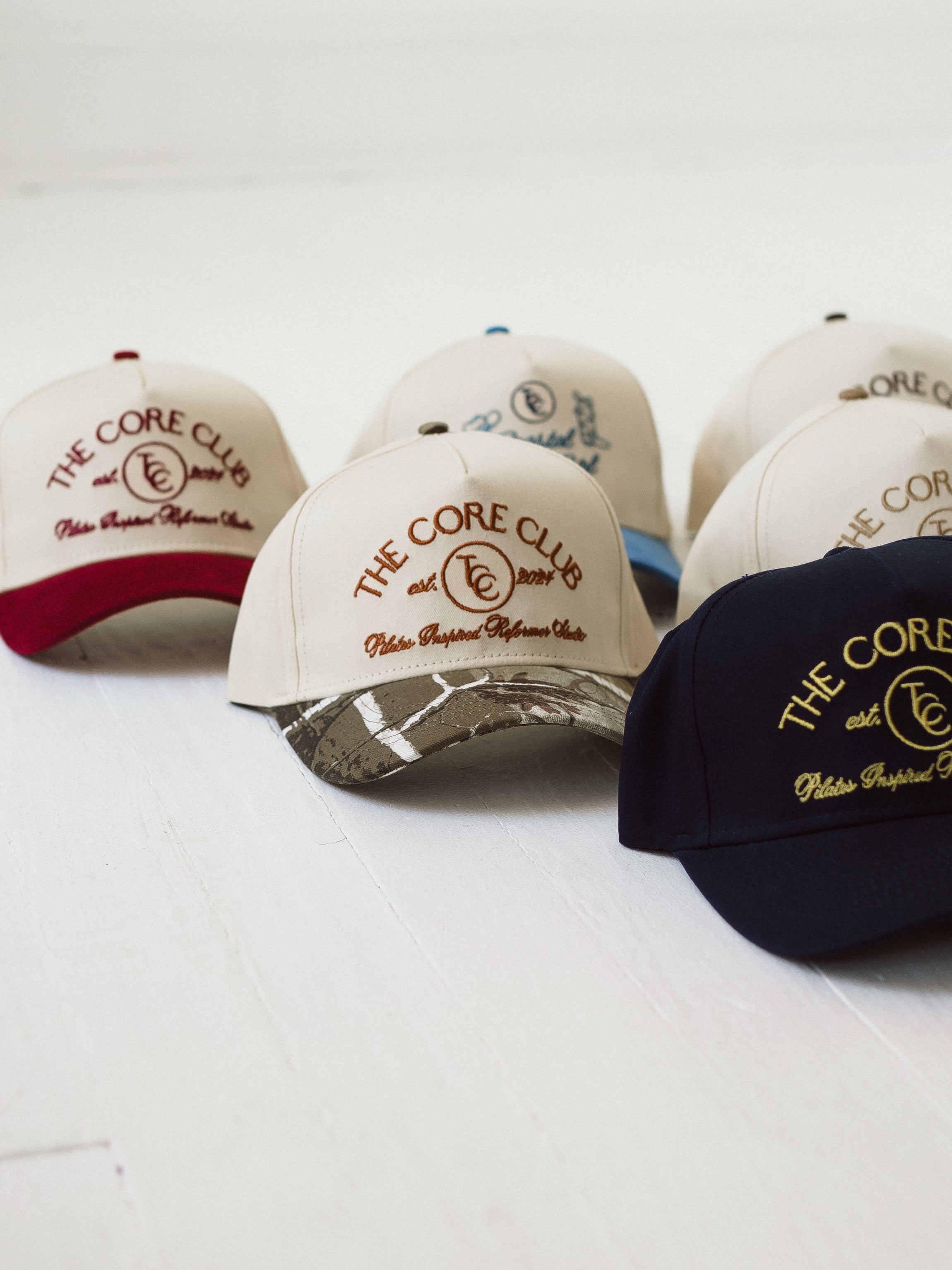 The Core Club pilates baseball hats in navy, camo hat, burgundy hat